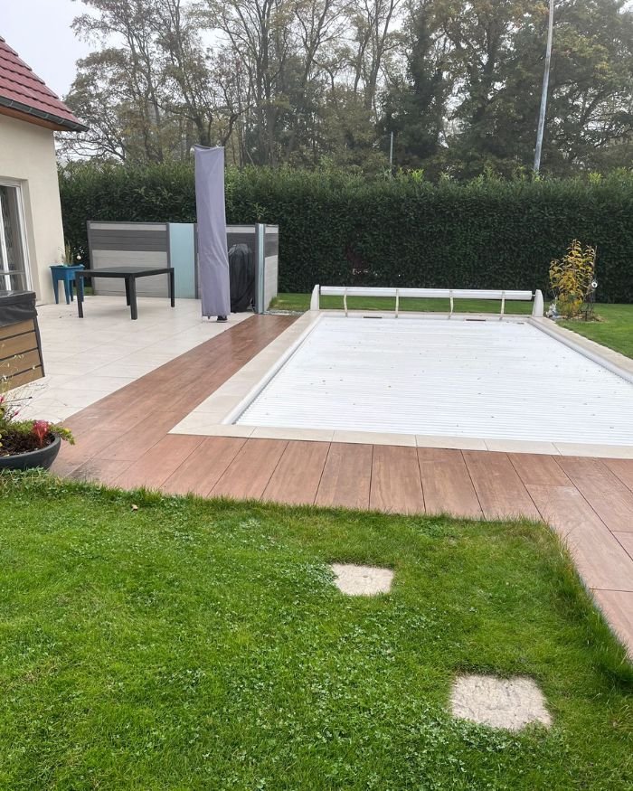 Terrasse en dalles autour d’une piscine avec aménagement paysager et gazon, réalisée à Mulhouse
